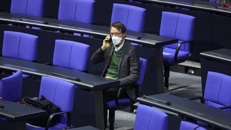 Karl Lauterbach sitzt allein mit Maske im Plenum des Deutschen Bundestages.