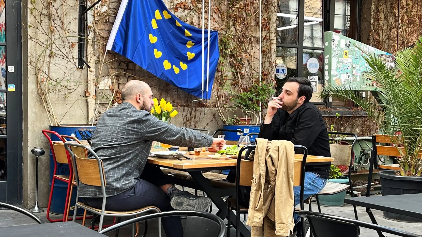 Zwei Männer spielen Schach in einem Café in Tiflis vor einer EU-Fahne.