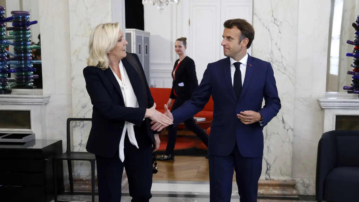 Rechtspopulistin Marine Le Pen und Präsident Emmanuel Macron geben sich die Hand.