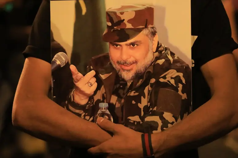 Ein Anhänger hält ein Plakat von Moktada al-Sadr in den Armen.