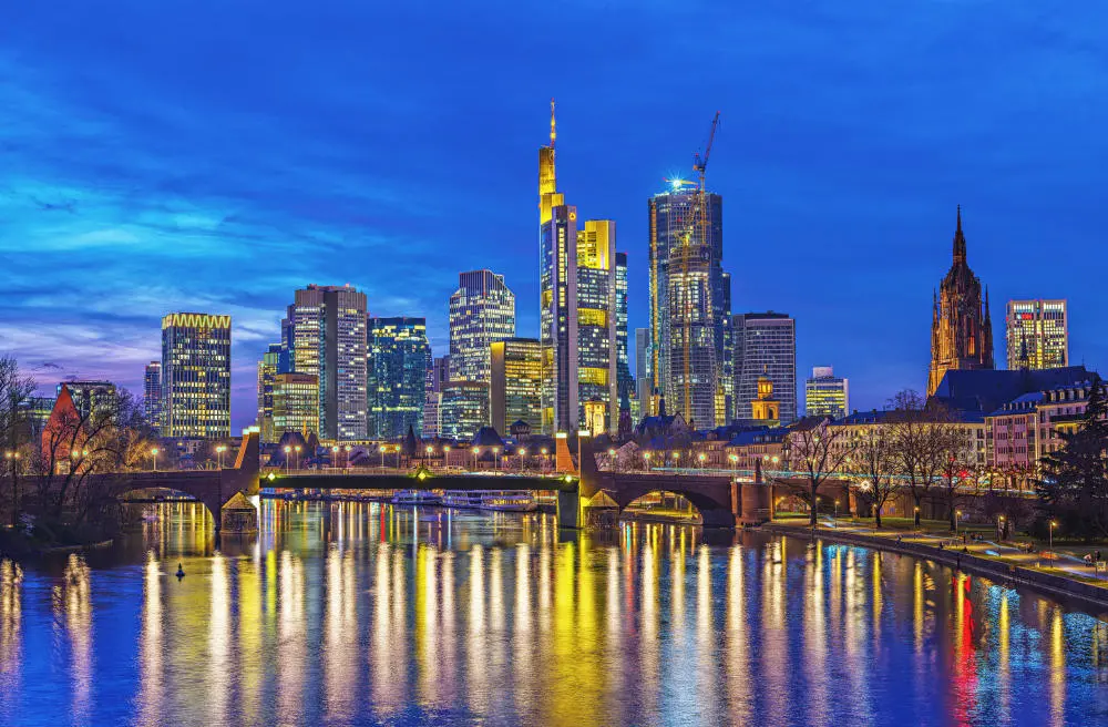 Die Frankfurter Skyline hinter dem Main zur blauen Stunde nach Sonnenuntergang.