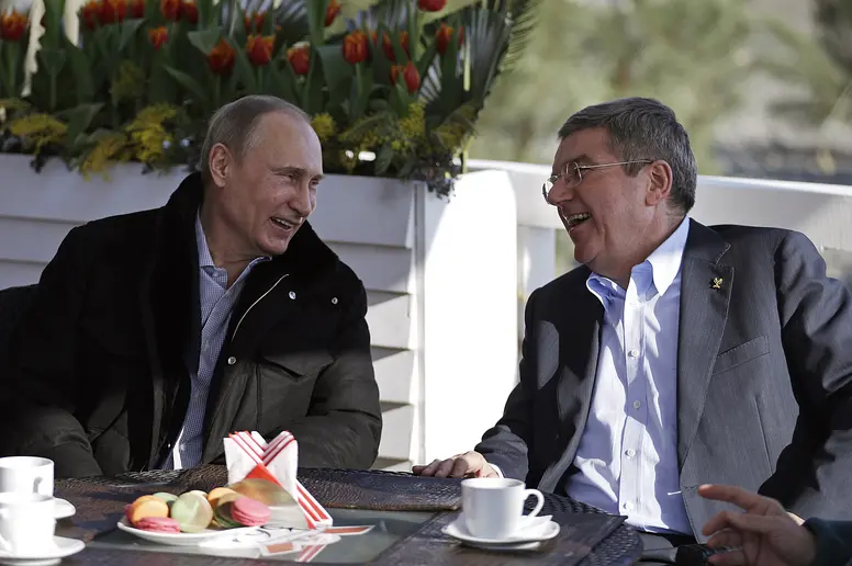 Vladimir Putin und Thomas Bach lachend während eines Gesprächs