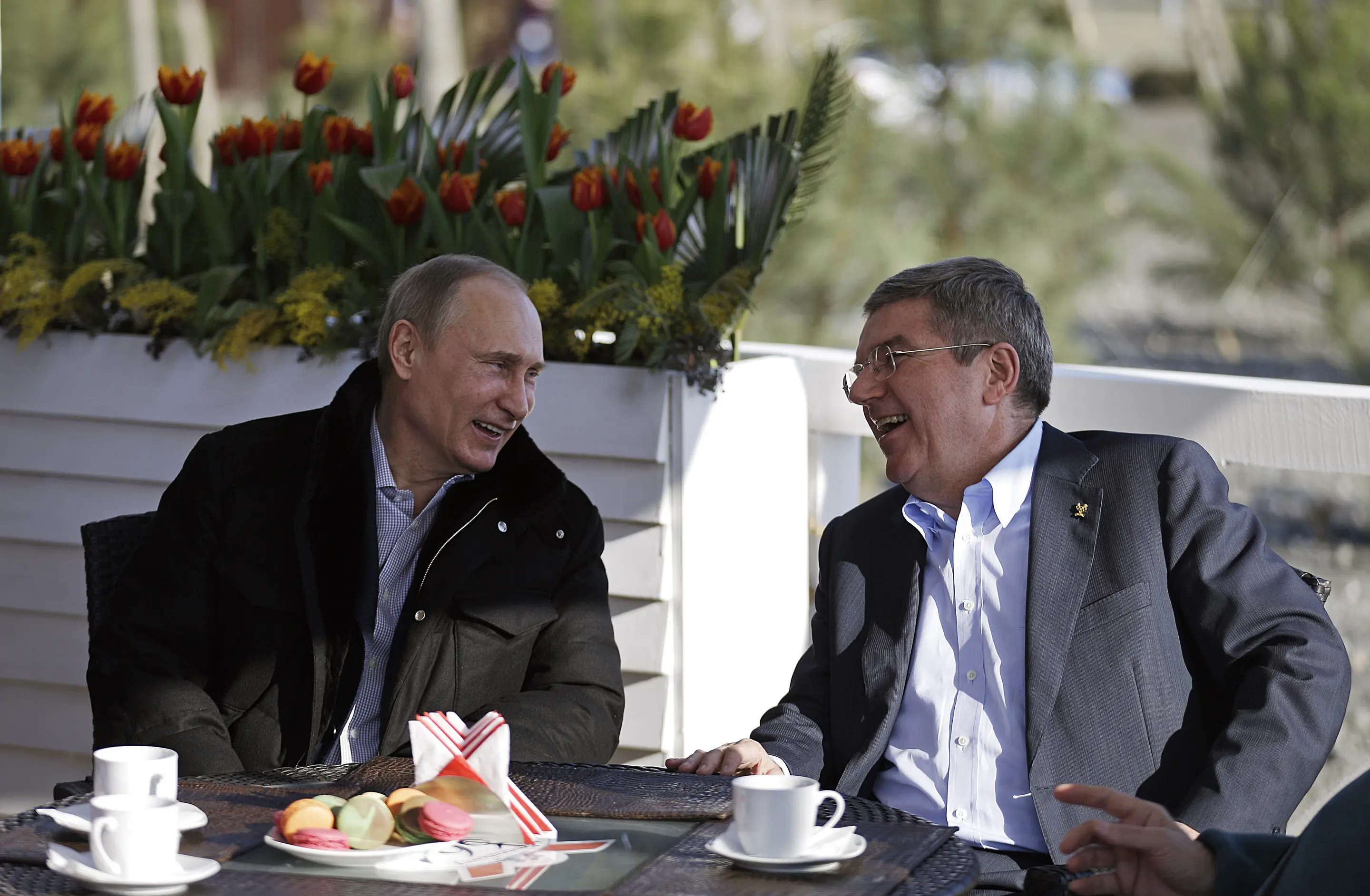 Vladimir Putin und Thomas Bach lachend während eines Gesprächs
