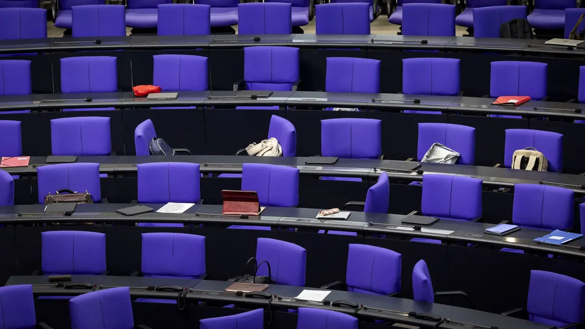 Auf den Stühlen und Tischen im Plenarsaal liegen Taschen und Unterlagen.