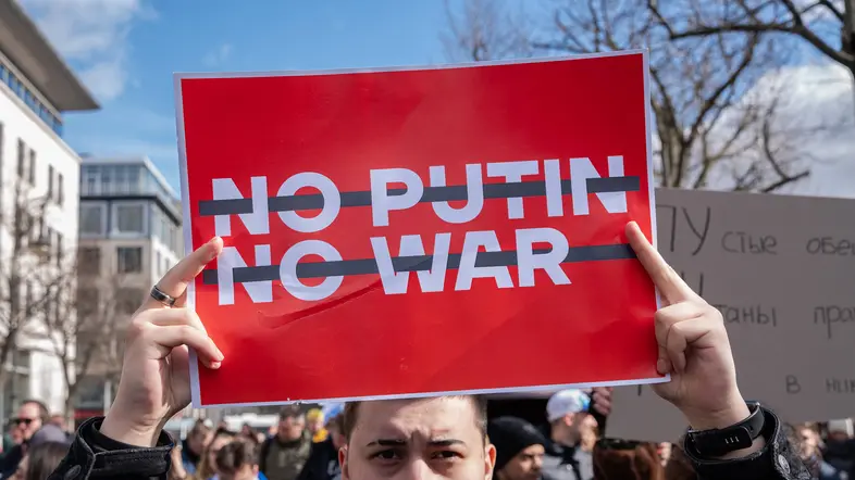 Demonstrant hält ein Schild mit "No Putin, No War" hoch.