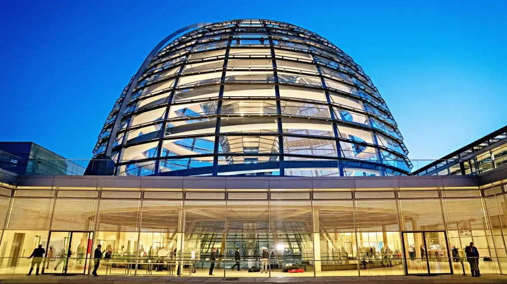 Blick auf die beleuchtete Reichstagskuppel und die Fraktionsebene.