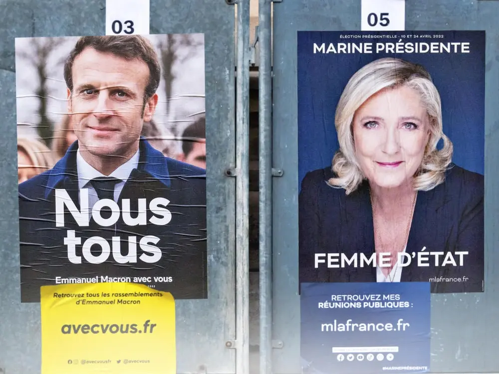 Zwei nebeneinander hängende Wahlplakate, für Emmanuel Macron und Marine Le Pen.