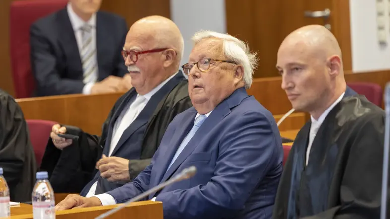 Das Bild zeigt Bankier Christian Olearius zwischen seinen Anwälten im Gerichtssaal.