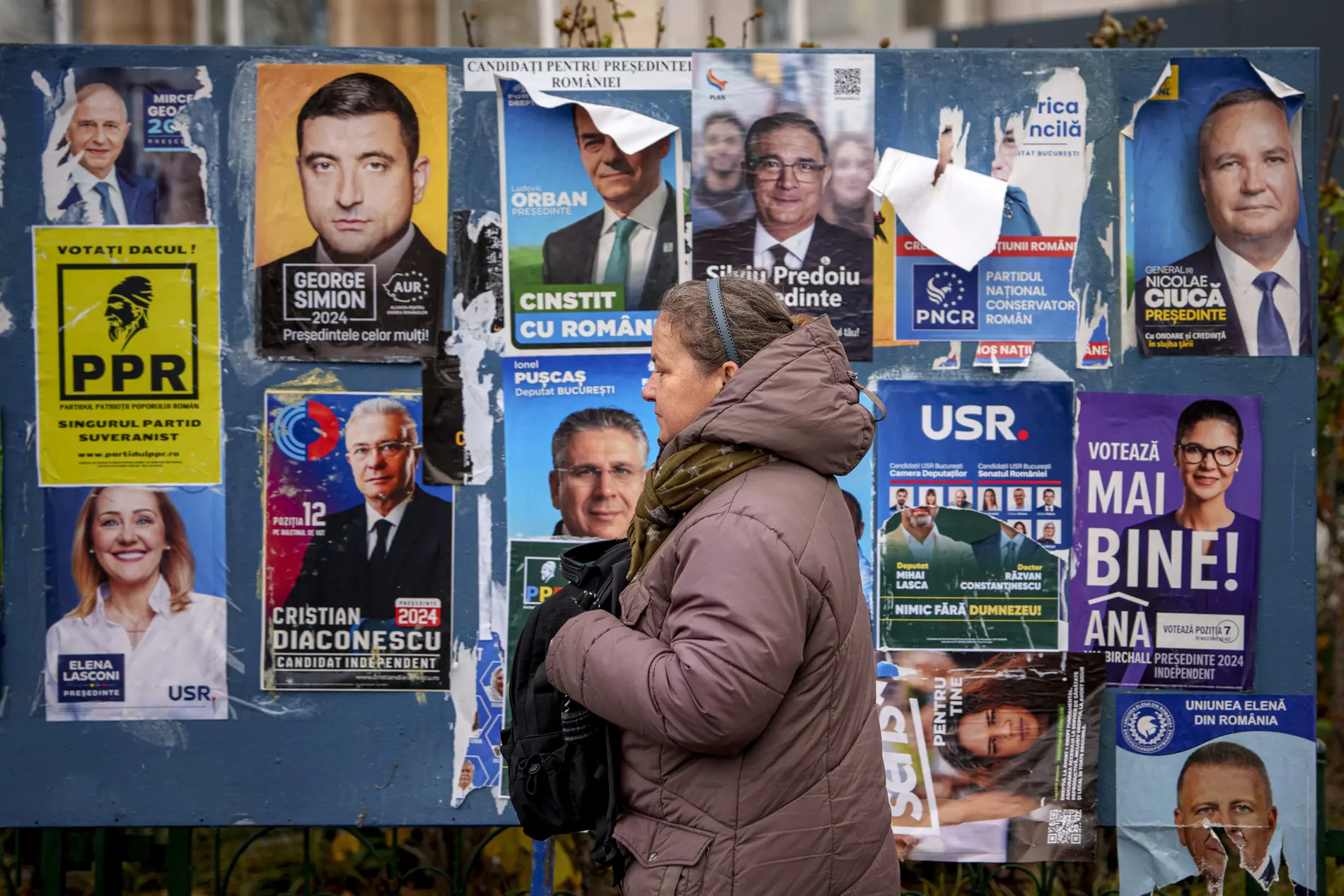 Eine Frau läuft an einer Ansammlung von Wahlkampfplakaten in Rumänien entlang