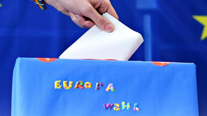 Wahlzettel wird in eine Wahlurne mit den EU-Sternen gesteckt 