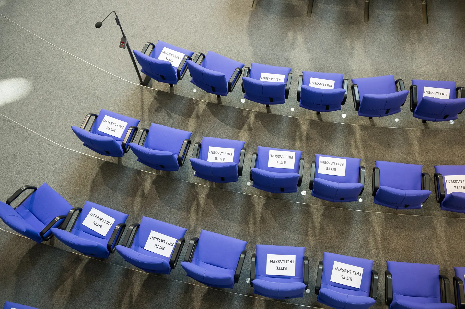 Schilder mit der Aufschrift "Bitte Freilassen" liegen auf Stühlen im Plenarsaal