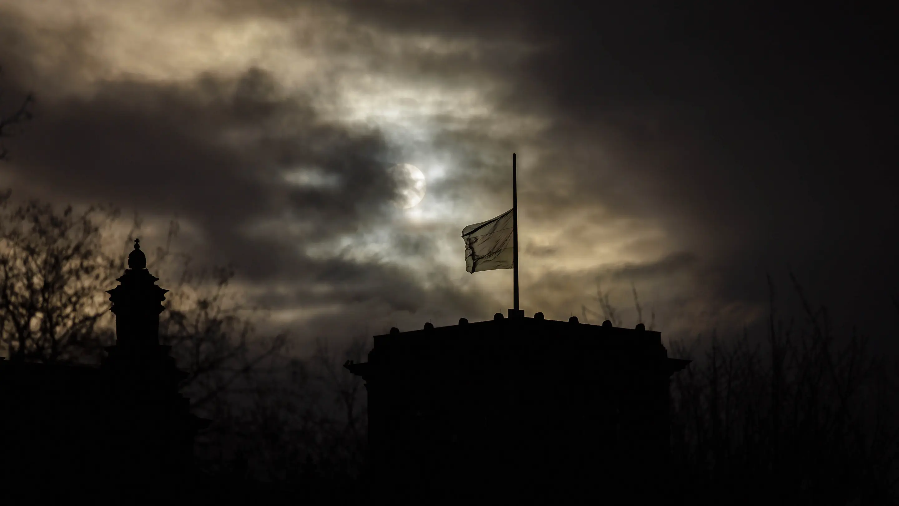 Flaggen wehen auf Halbmast auf dem Reichstagsgebäude, dunkler Himmel