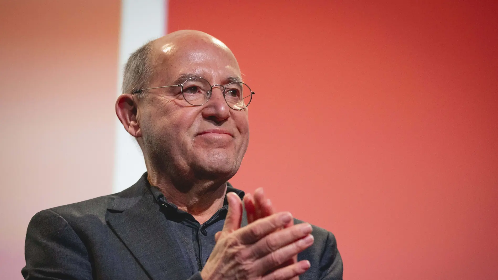 Gregor Gysi klatscht in die Hände vor einer roten Wand