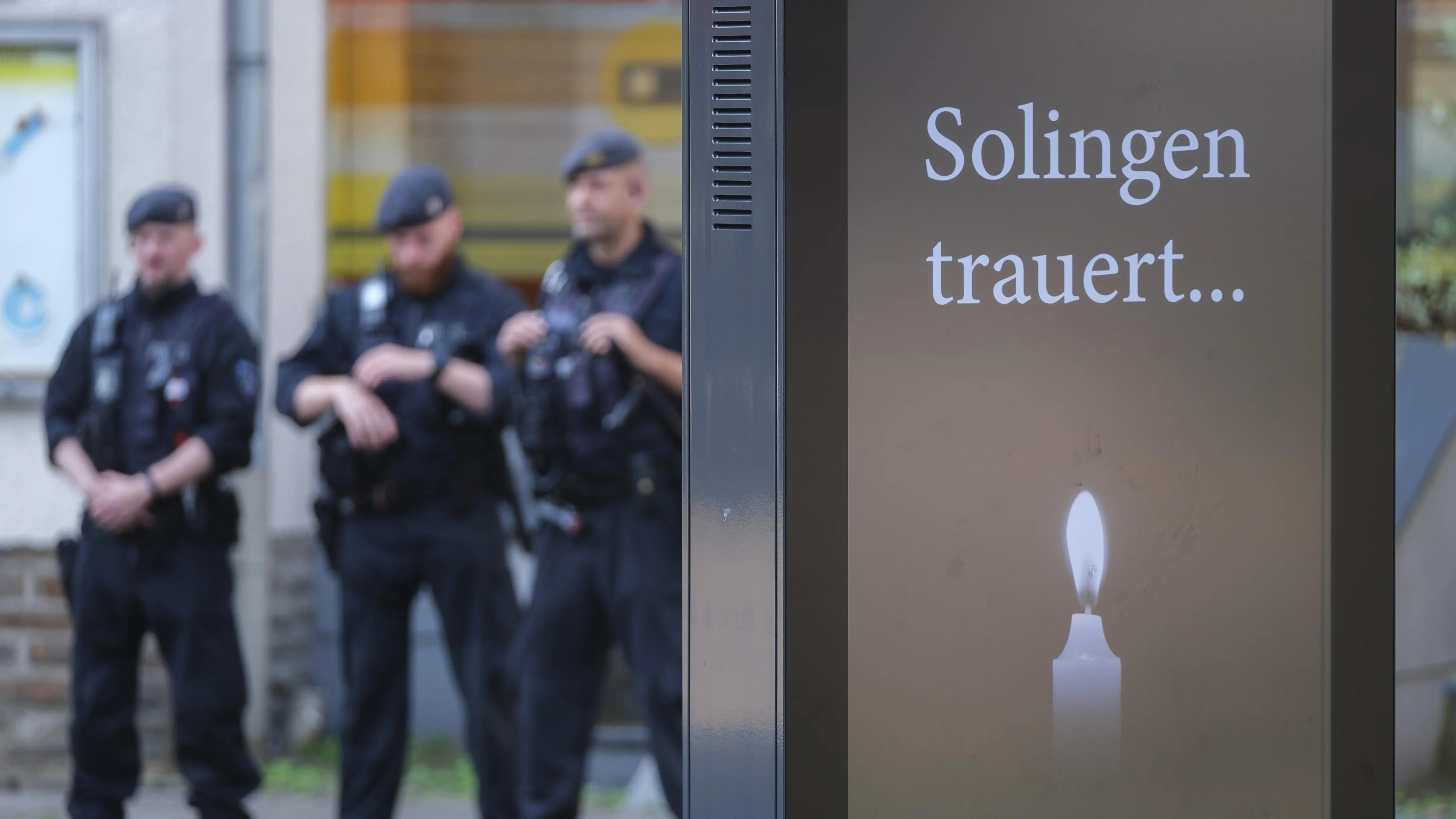 Polizisten stehen hinter einer Anzeigentafel "Solingen trauert …".