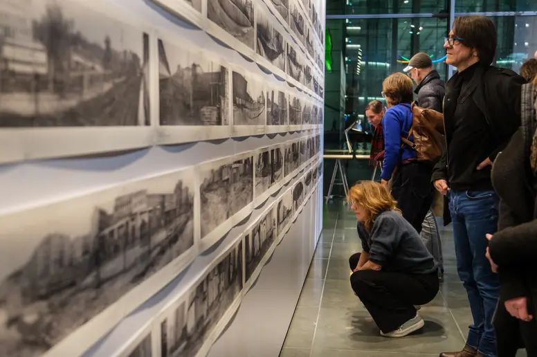 Besucher der Ausstellung blicken auf Bilder der Berliner Mauer