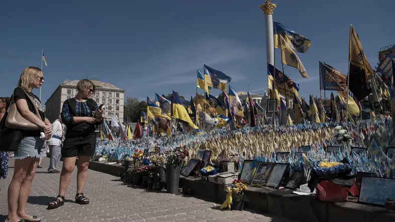 Passanten betrachten Nationalflaggen mit Namen der Gefallenen im Ukrainekrieg.