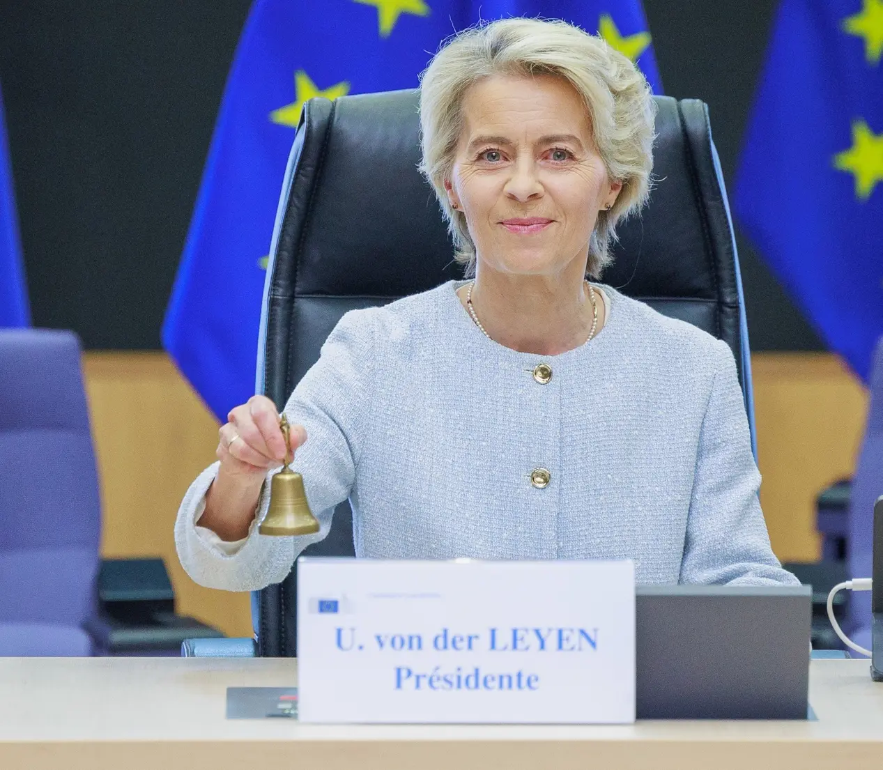 Ursula von der Leyen mit Glocke vor EU-Flaggen