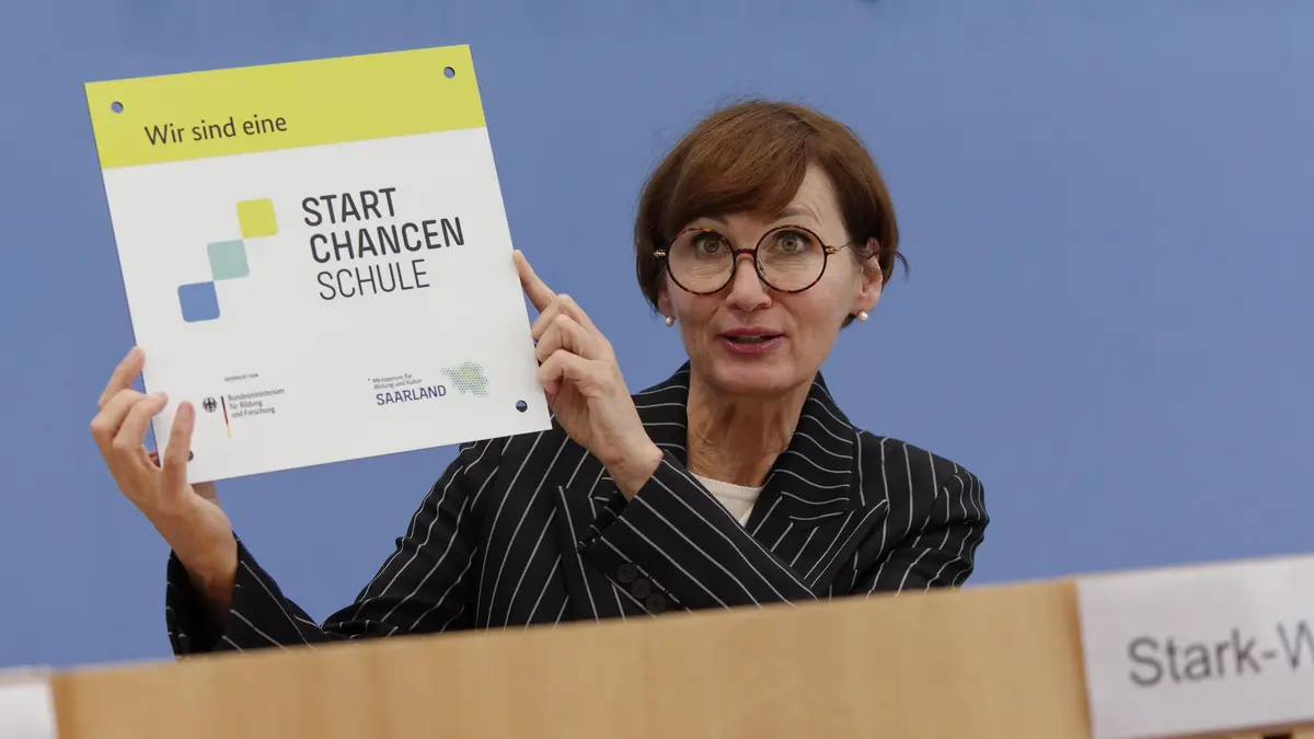 Bettina Stark-Watzinger hält ein Schild hoch.