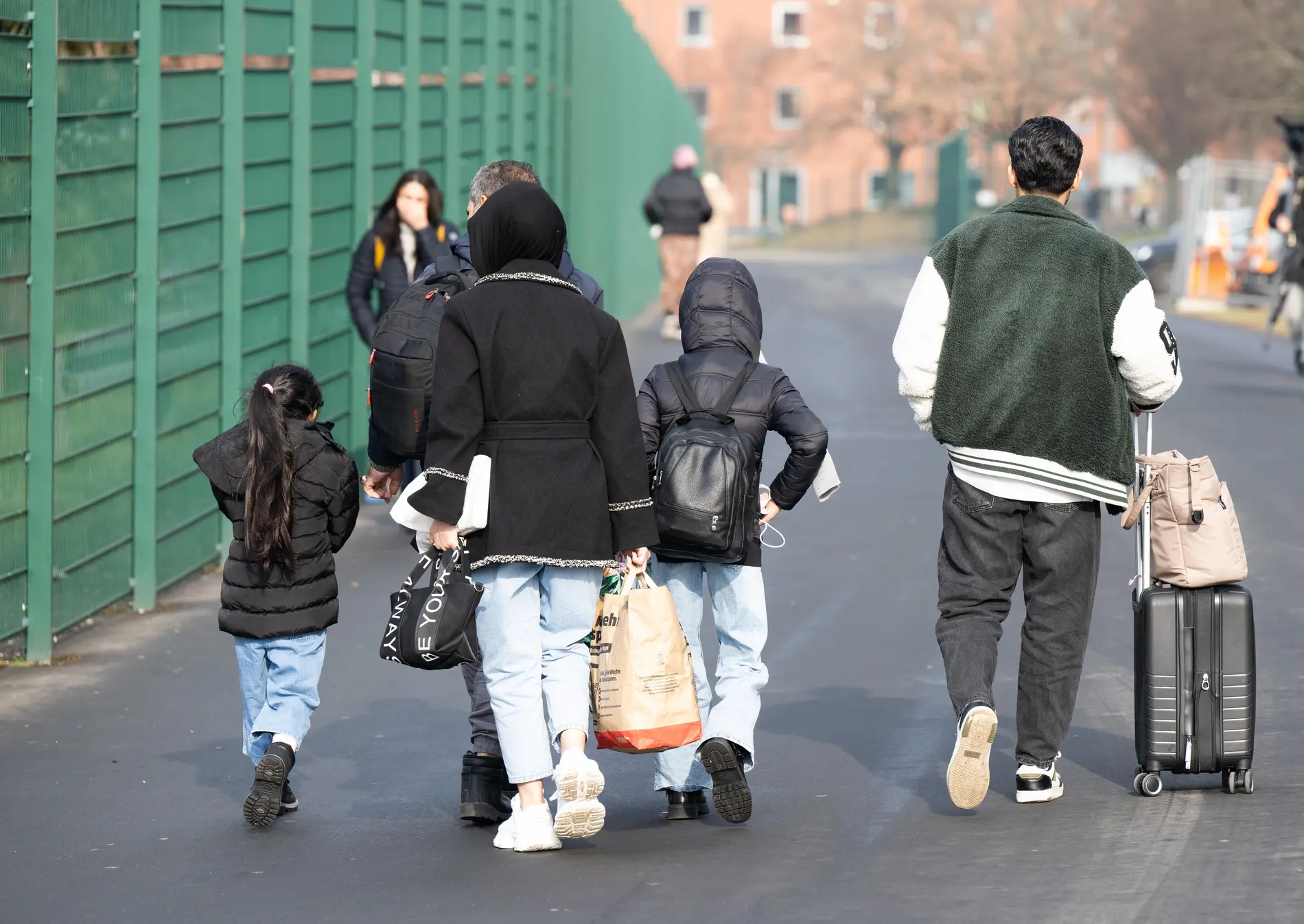 Flüchtlinge gehen in der hessischen Erstaufnahmeeinrichtung für Flüchtlinge in Gießen zu einer Unterkunft. 