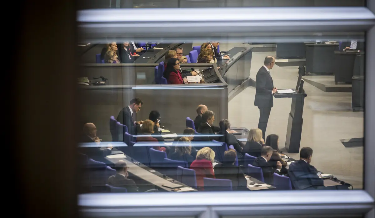 Blick durch ein Fenster auf die Regierungsbank und Friedrich Merz am Rednerpult