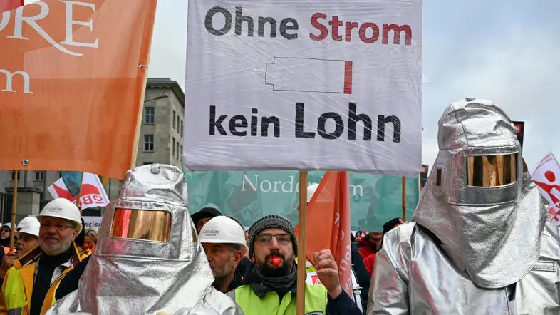 Demonstranten halten ein Plakat mit der Aufschrift „Ohne Strom kein Lohn“.