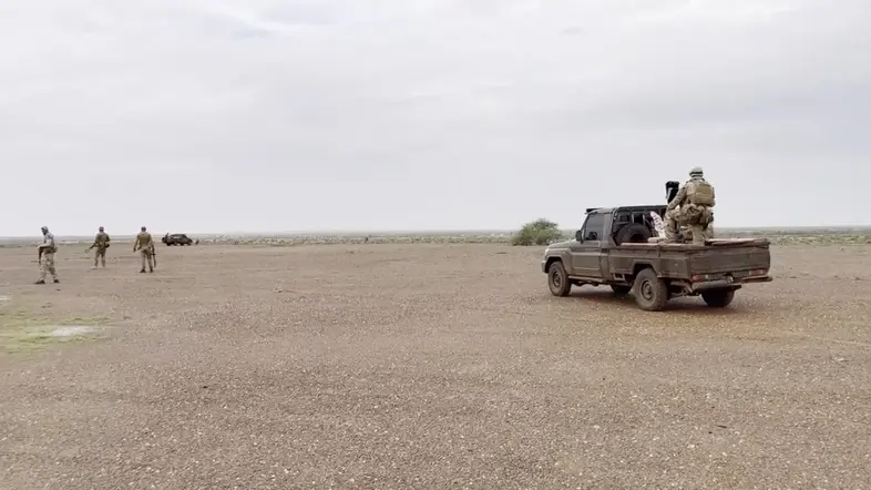 Ein Auto und mehrere Soldaten auf einem kargen Stück Land in Afrika