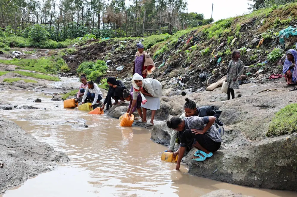 Mehrere Frauen füllen Eimer mit Wasser an einem Fluss in Äthiopien