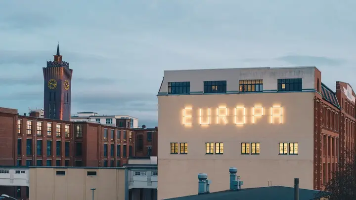 Eine Hauswand mit "Europa"-Schriftzug, links ein Kirchenturm