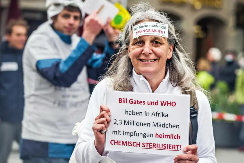 Eine Demonstrantin hat ein Schild auf der Stirn, auf dem steht, dass sie eine Impfpflicht ablehnt.