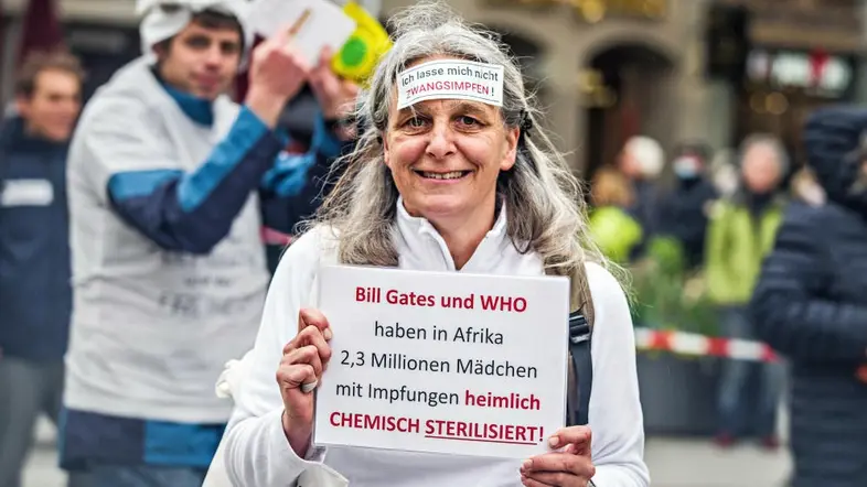 Eine Demonstrantin hat ein Schild auf der Stirn, auf dem steht, dass sie eine Impfpflicht ablehnt.