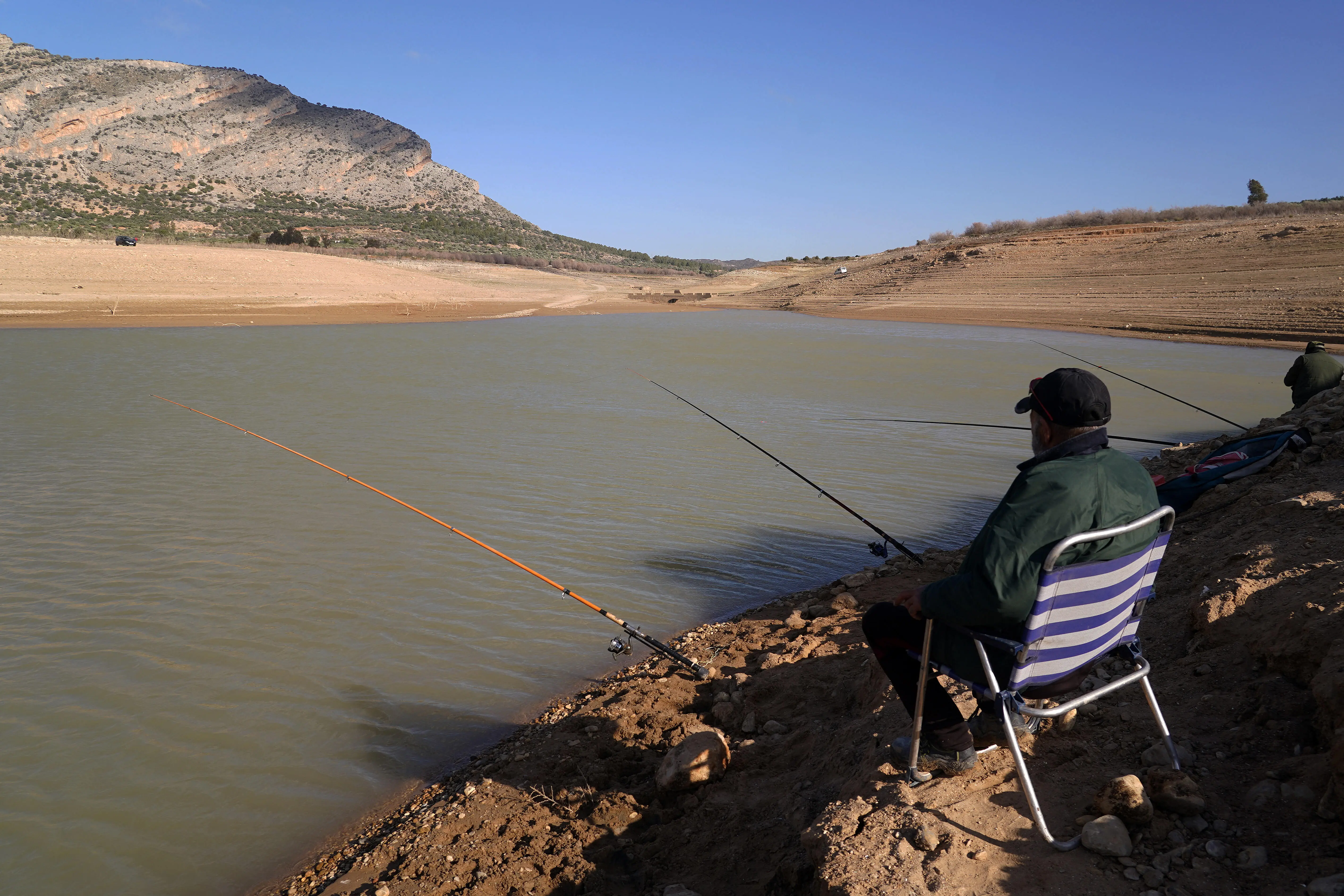 Zwei Angler sitzen an einem fast ausgetrockneten See in Andalusien