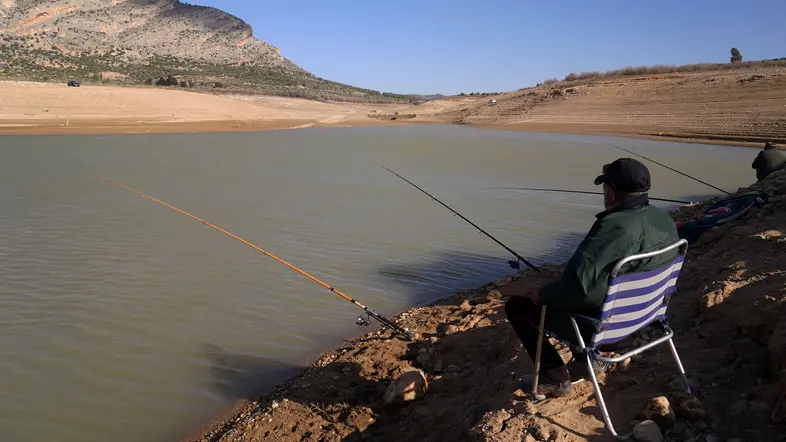 Zwei Angler sitzen an einem fast ausgetrockneten See in Andalusien