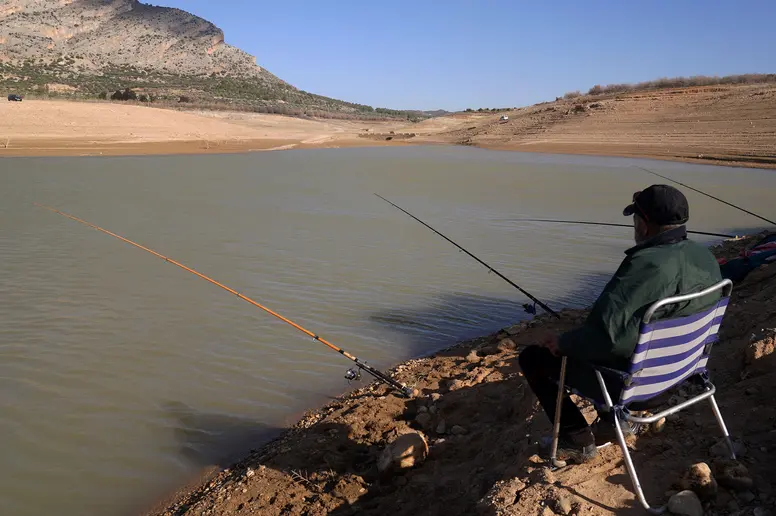 Zwei Angler sitzen an einem fast ausgetrockneten See in Andalusien