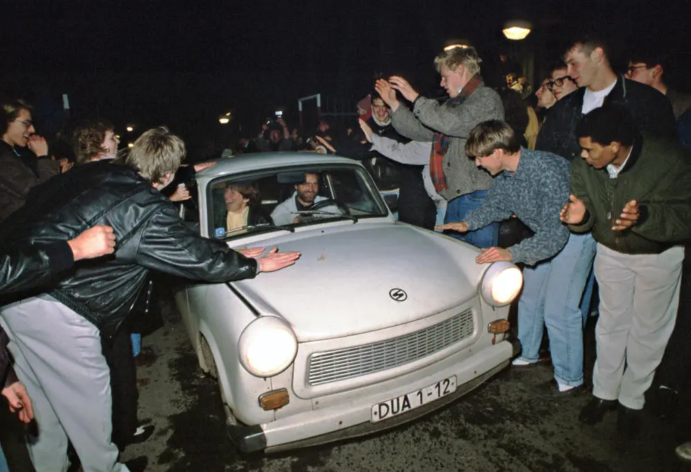 Ein Trabbi wird an der Deutsch-Deutschen Grenze von Menschen begrüßt.