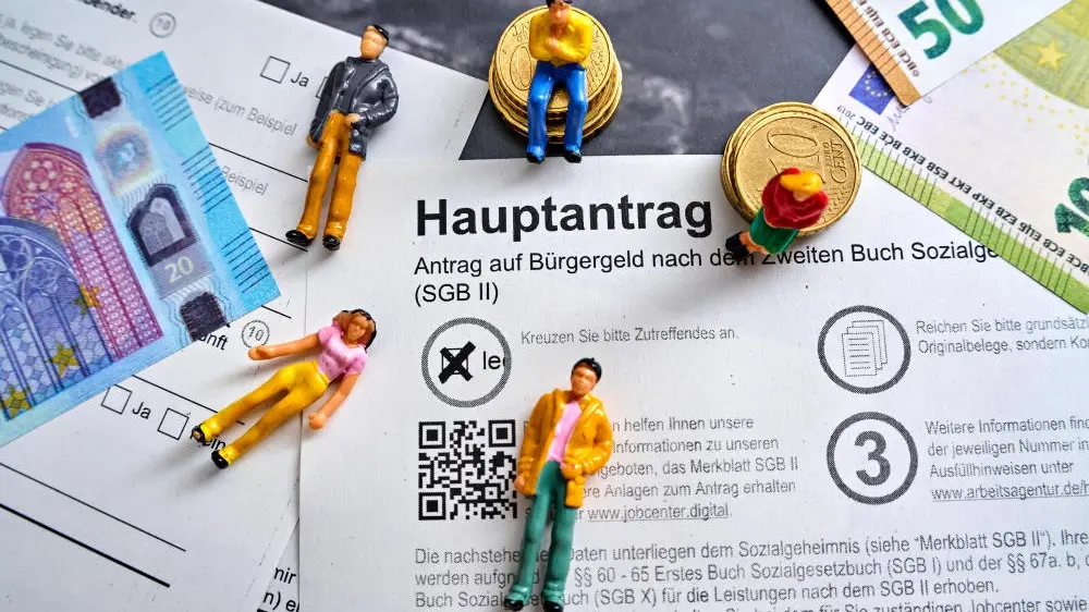 Bürgergeld-Hauptantrag mit Euro Geldscheinen und Menschen Figuren