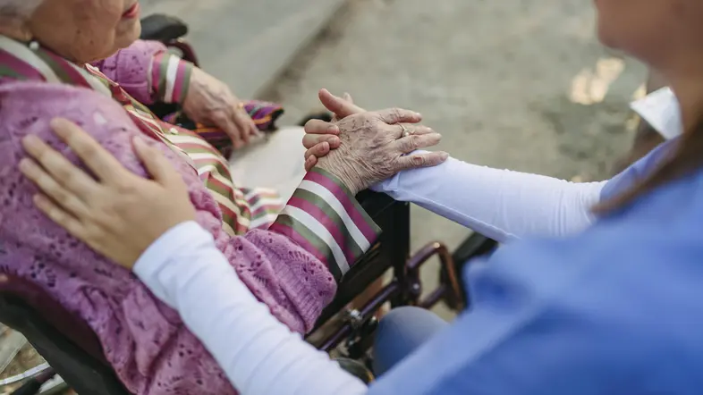 Eine Pflegekraft hält die Hand einer älteren Dame.